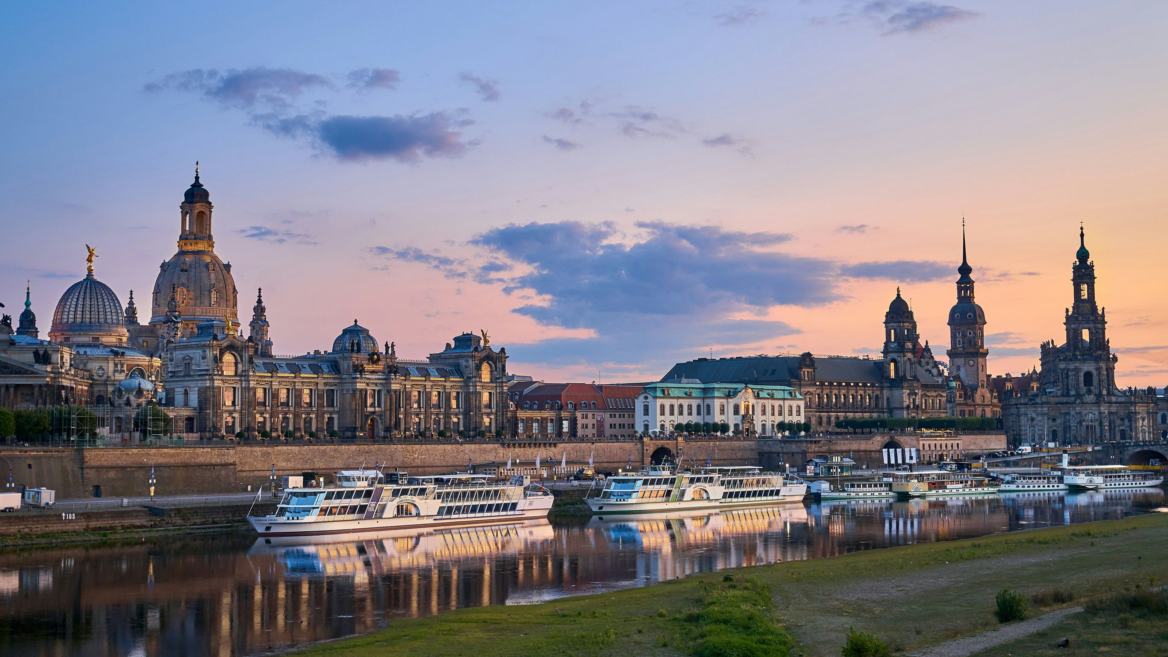 Dresdner Altstadt-Silhouette an der Elbe bei Sonnenuntergang mit Frauenkirche und Ausflugsschiffen am Ufer